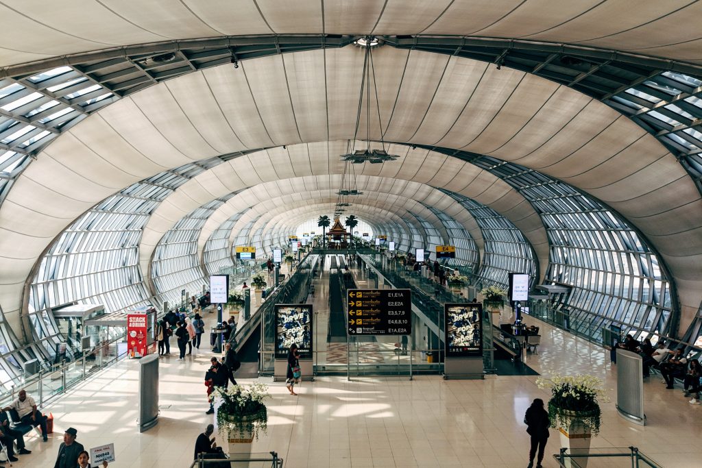 En lufthavn summende af mennesker i en stor og lang gang, der forbinder én terminal med en anden.